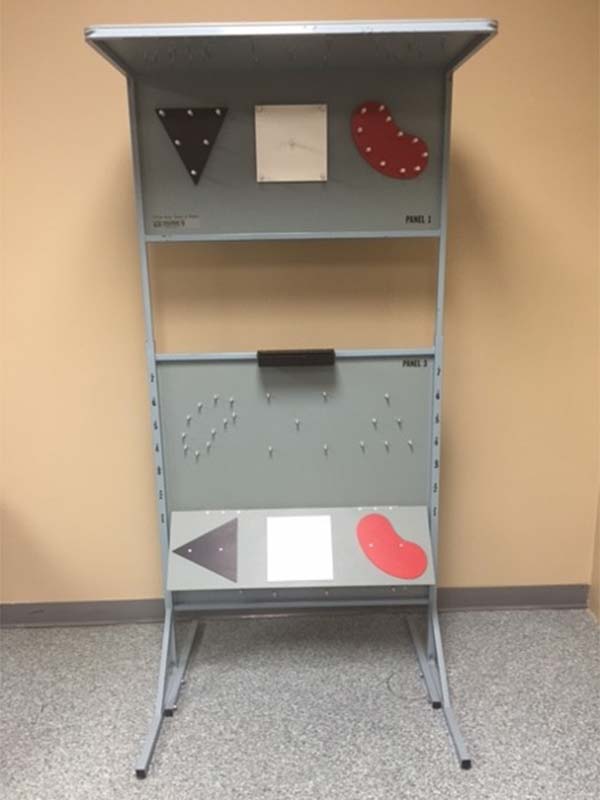 Tool used in the vocational assessment program to determine an individuals' whole body range of motion. Tool is a grey painted vertical stand with a number of movable components.