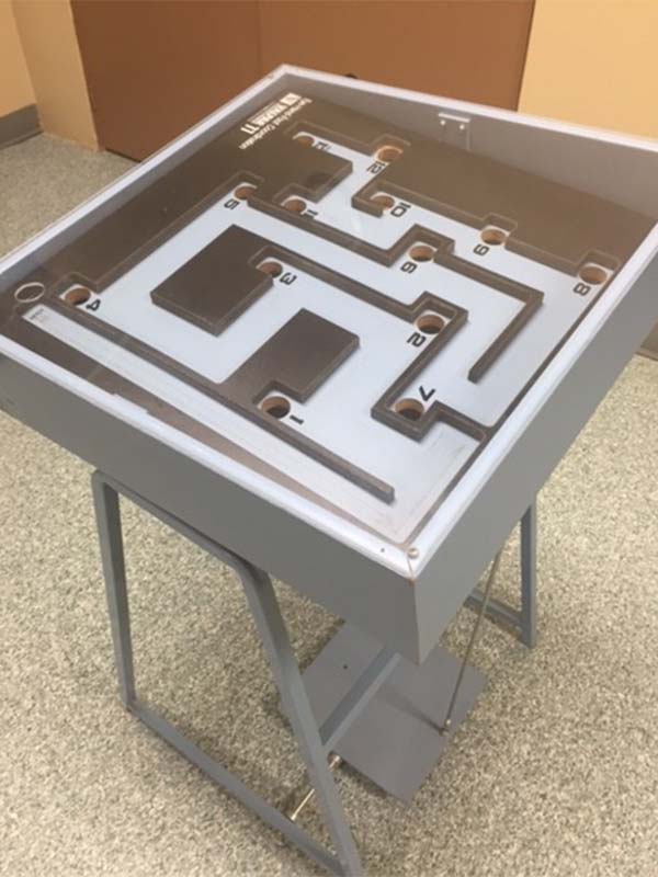 Tool used in the vocational assessment program to determine an individuals' eye-hand-foot coordination. Tool is a grey painted table top maze-type device which can tilt at multiple angles.